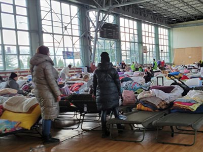 refugees sleep on cots lined up end to end